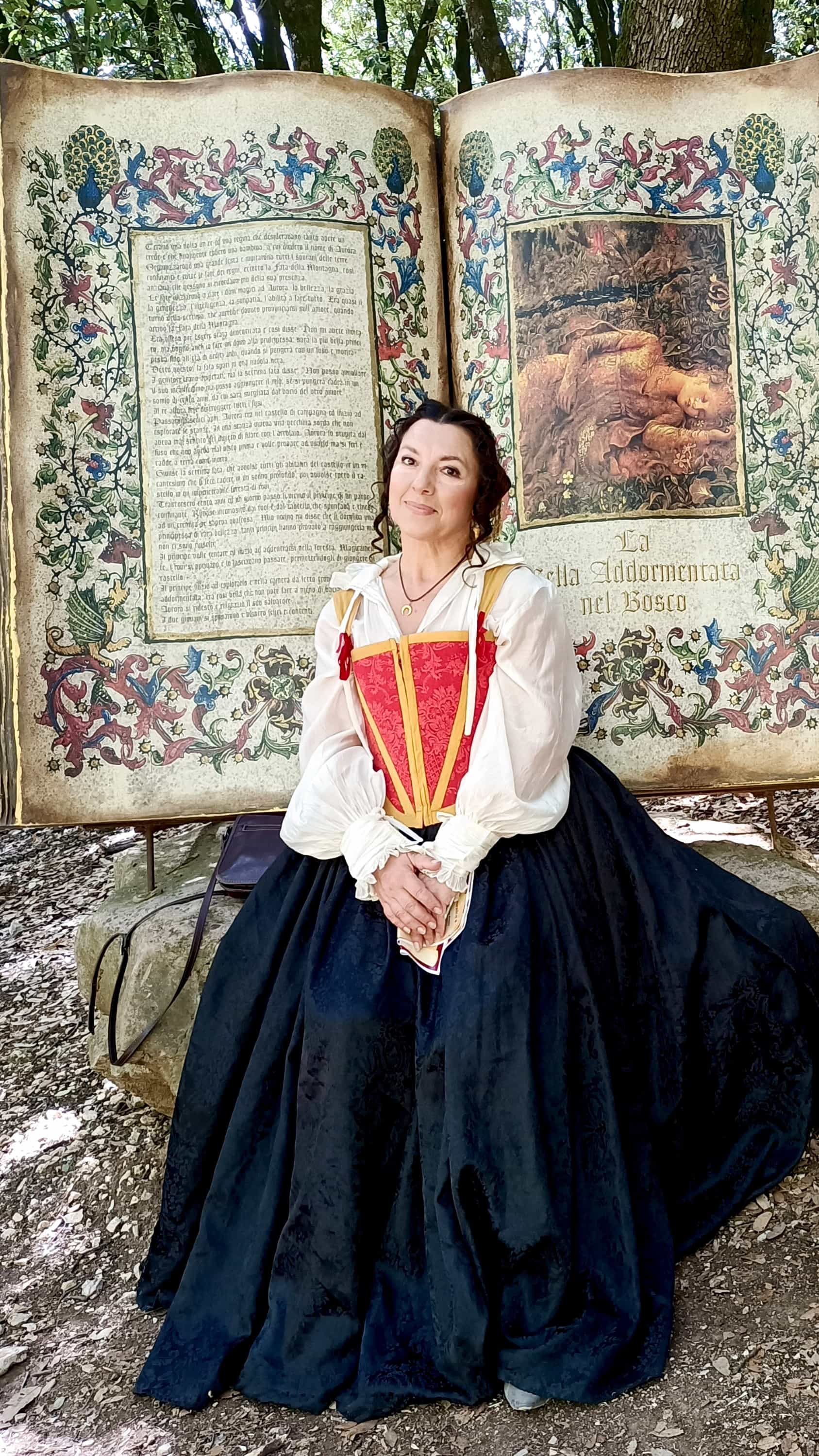 Olga in costume rinascimentale davanti a un grande libro scenografico dedicato a La Bella Addormentata nel Bosco