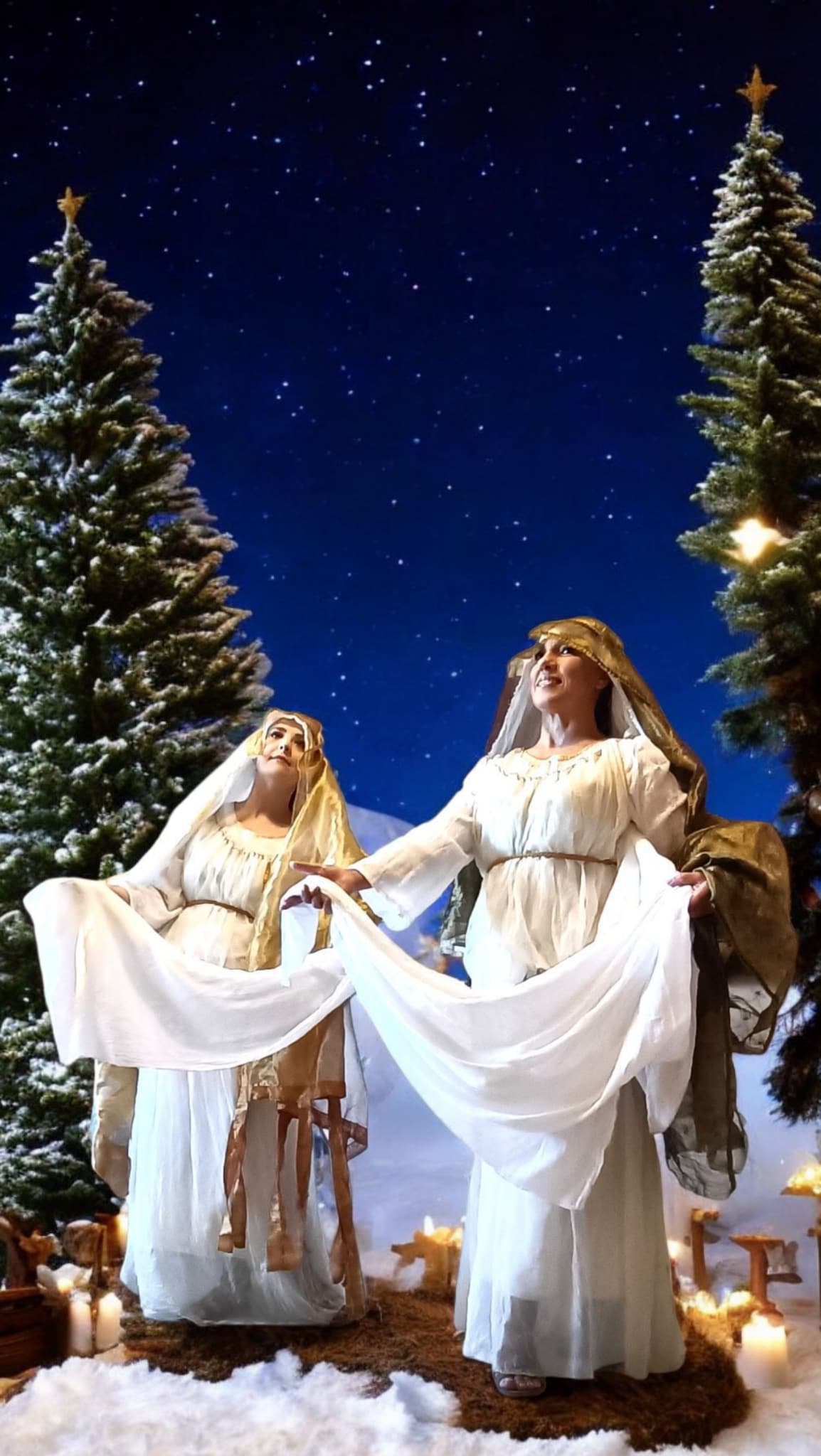 Angeli danzanti in costumi storici durante una scena del presepe vivente, con ambientazione natalizia all’aperto.